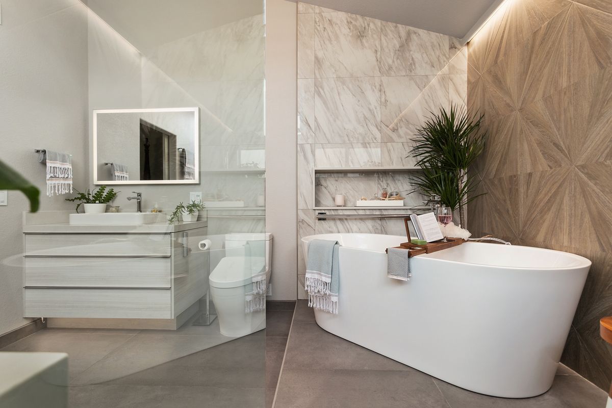 A bathroom with a tub , sink , toilet and mirror.