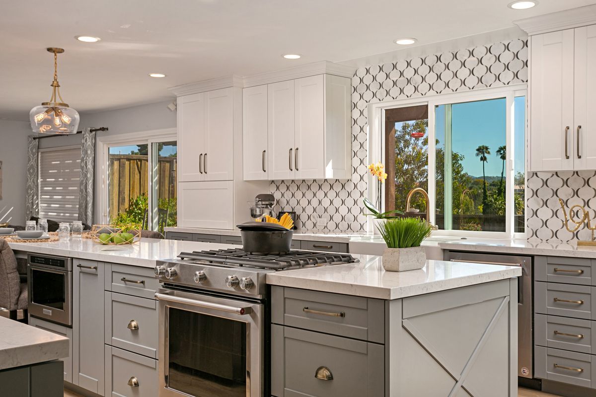 A kitchen with white cabinets , stainless steel appliances , and a large island.