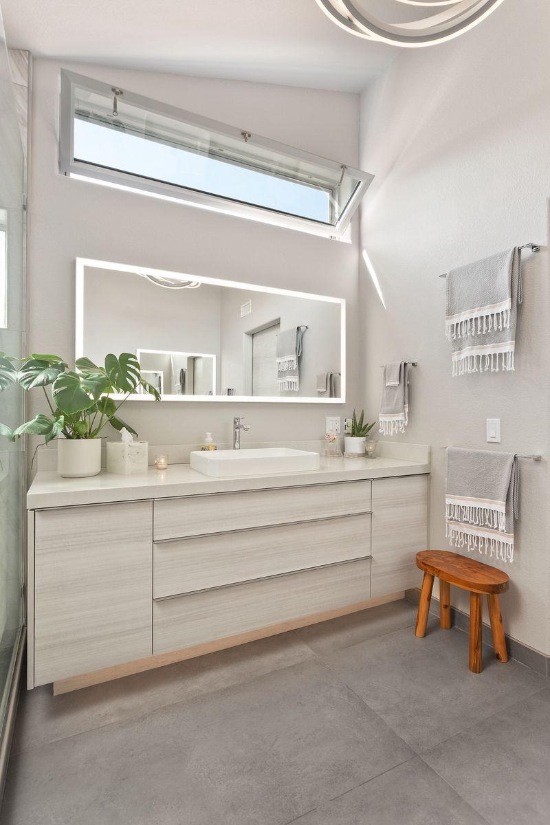 A bathroom with two sinks , a large mirror and a window.