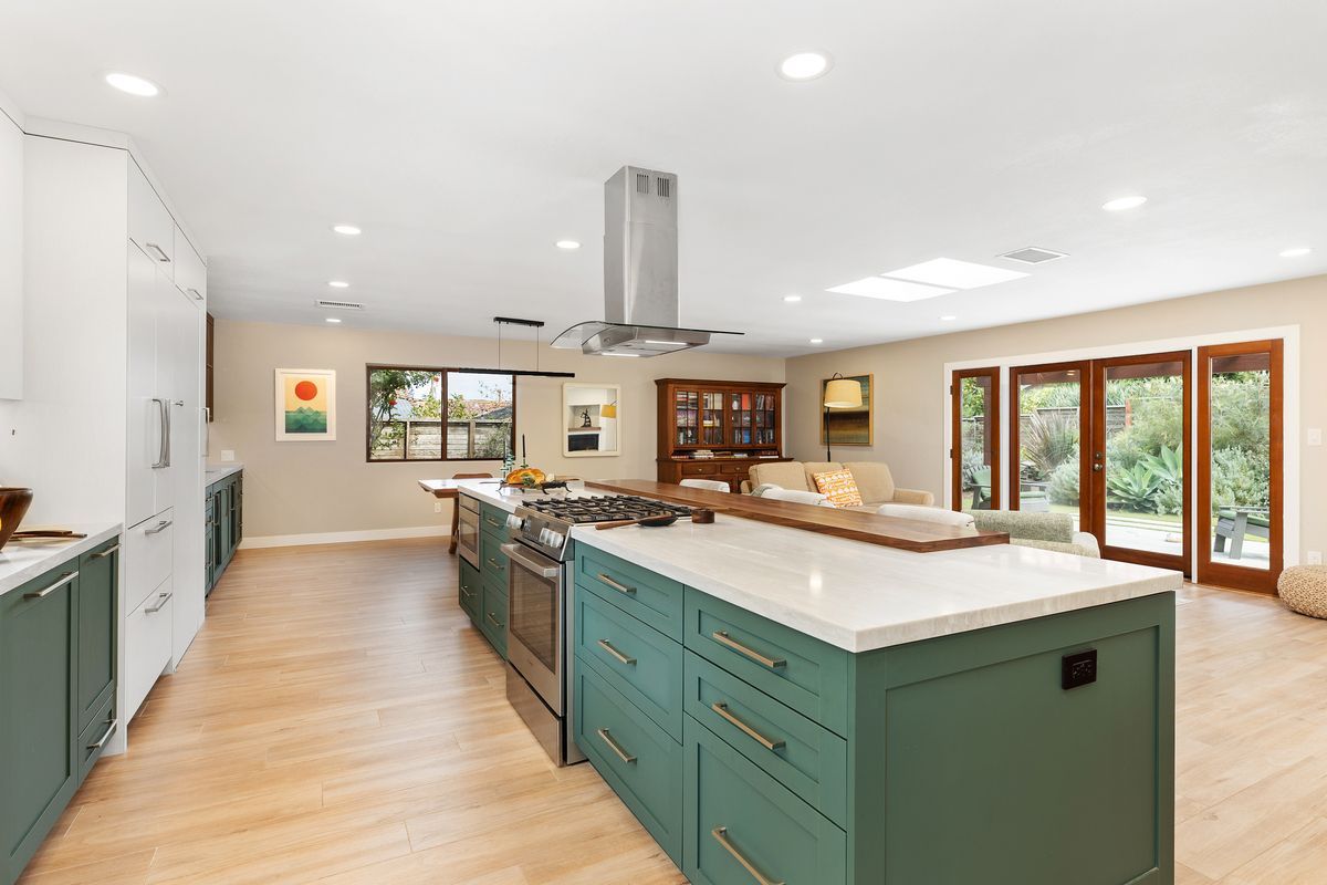 A kitchen with white cabinets , stainless steel appliances , a sink , and a large window.