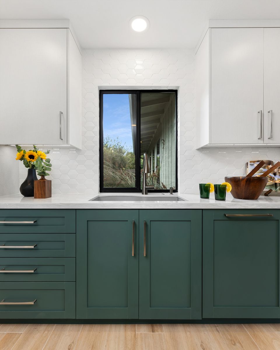 A kitchen with white cabinets , stainless steel appliances , a sink and an oven.