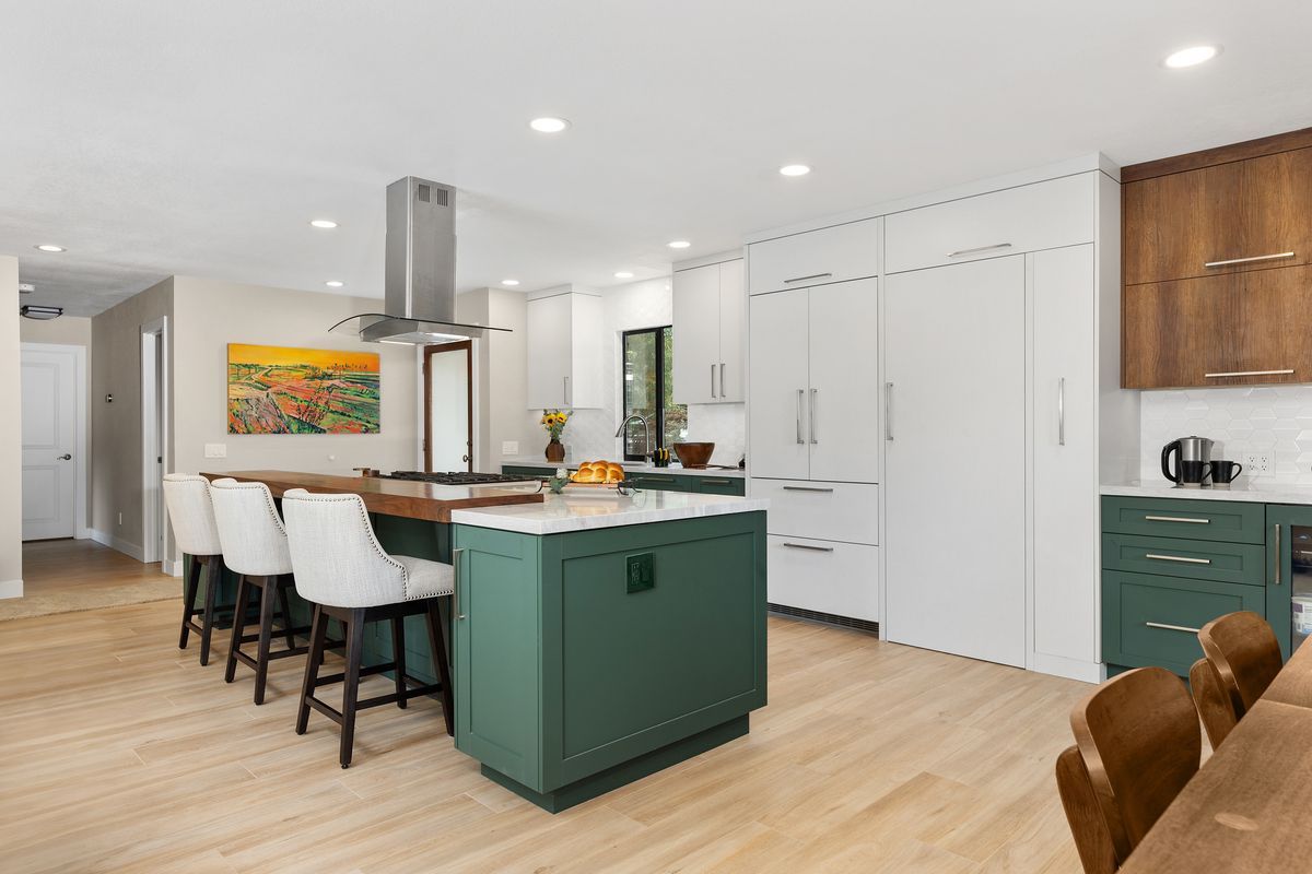A kitchen cabinet with the door open and a cork board on the wall.