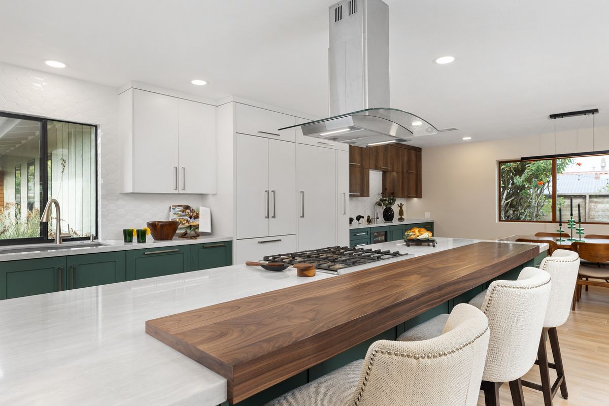 A kitchen with white cabinets and a flat screen tv on the wall.