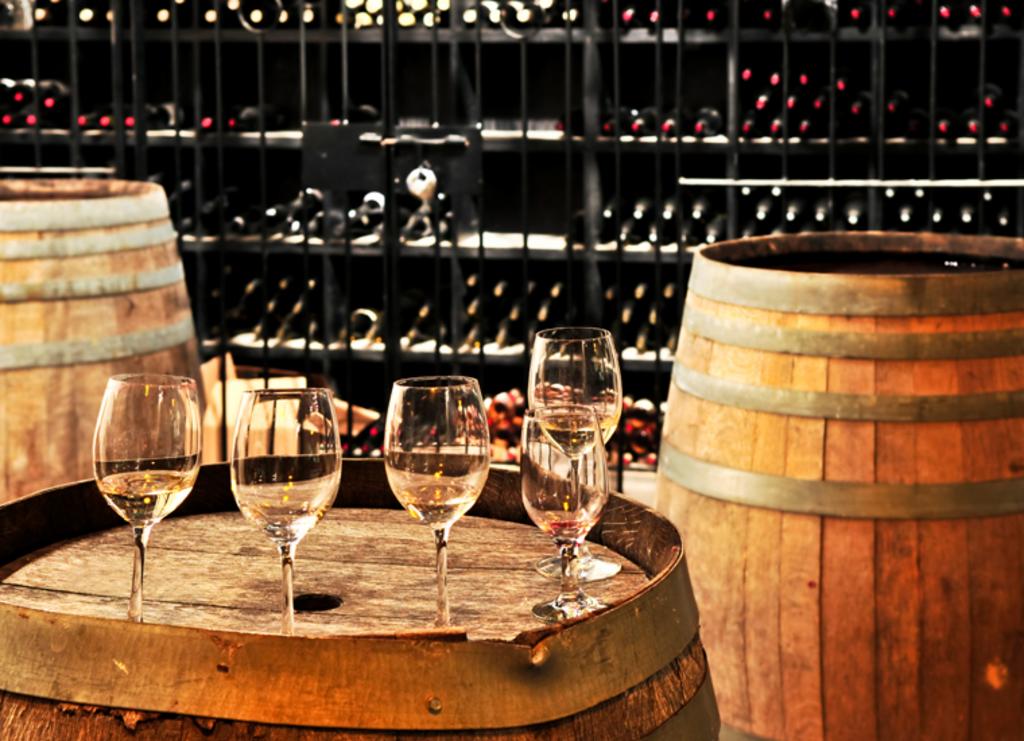 3 wine barrels with wine glasses on one barrel
