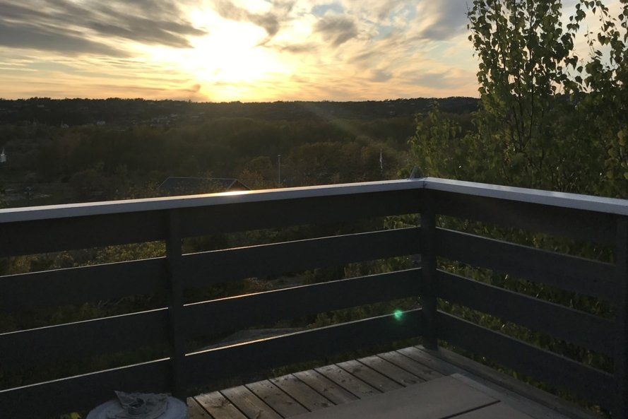 A balcony with a view of a sunset over a forest