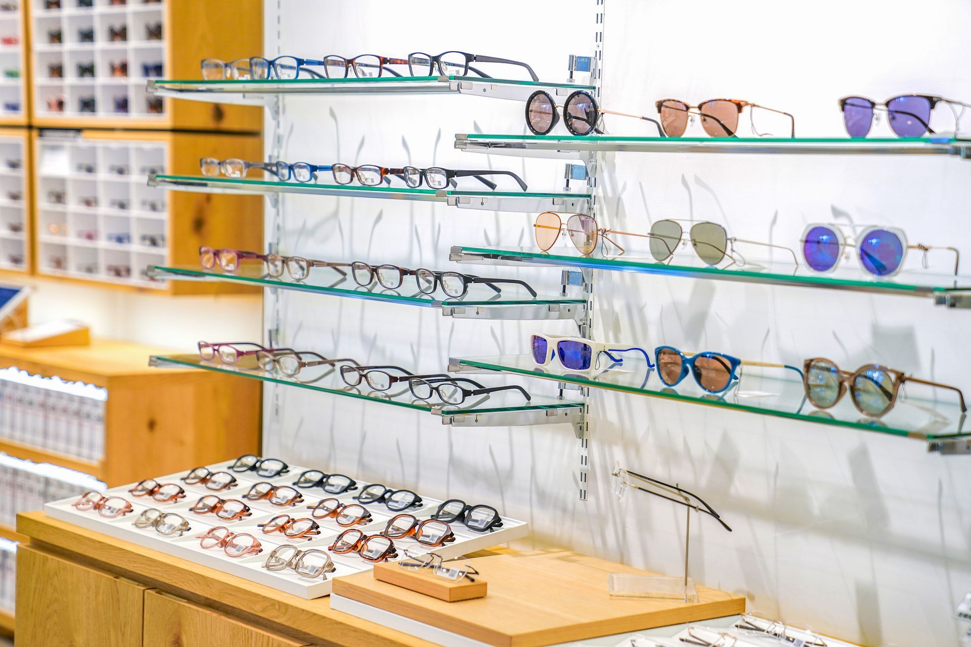Eyeglass frames displayed on glass shelves in a brightly lit optical shop.