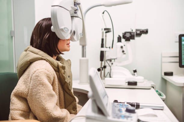Woman undergoing an eye exam, using equipment with lights, in a doctor's office.