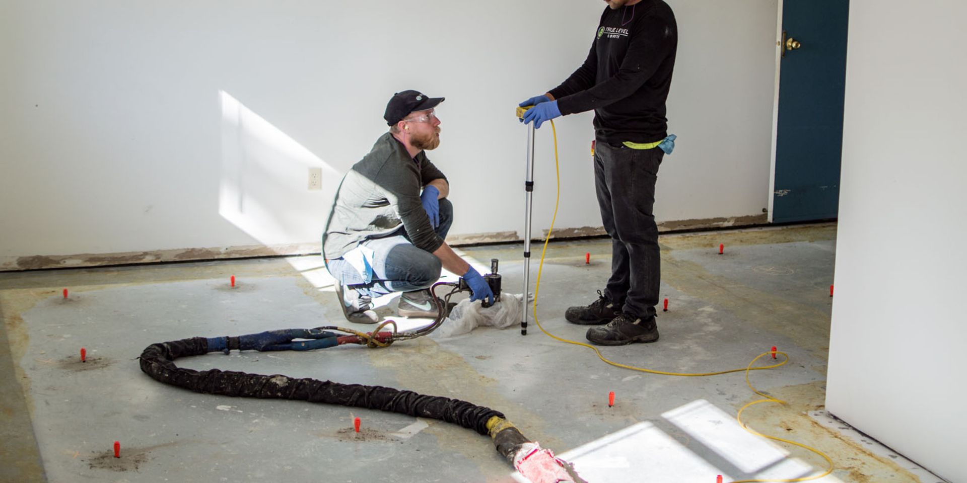 Two men are working on a floor in a room.