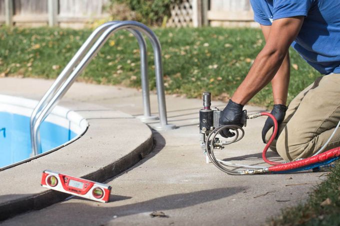 A man is working on the side of a swimming pool.