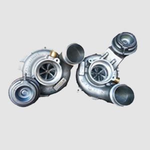 Two turbochargers are sitting next to each other on a white surface.