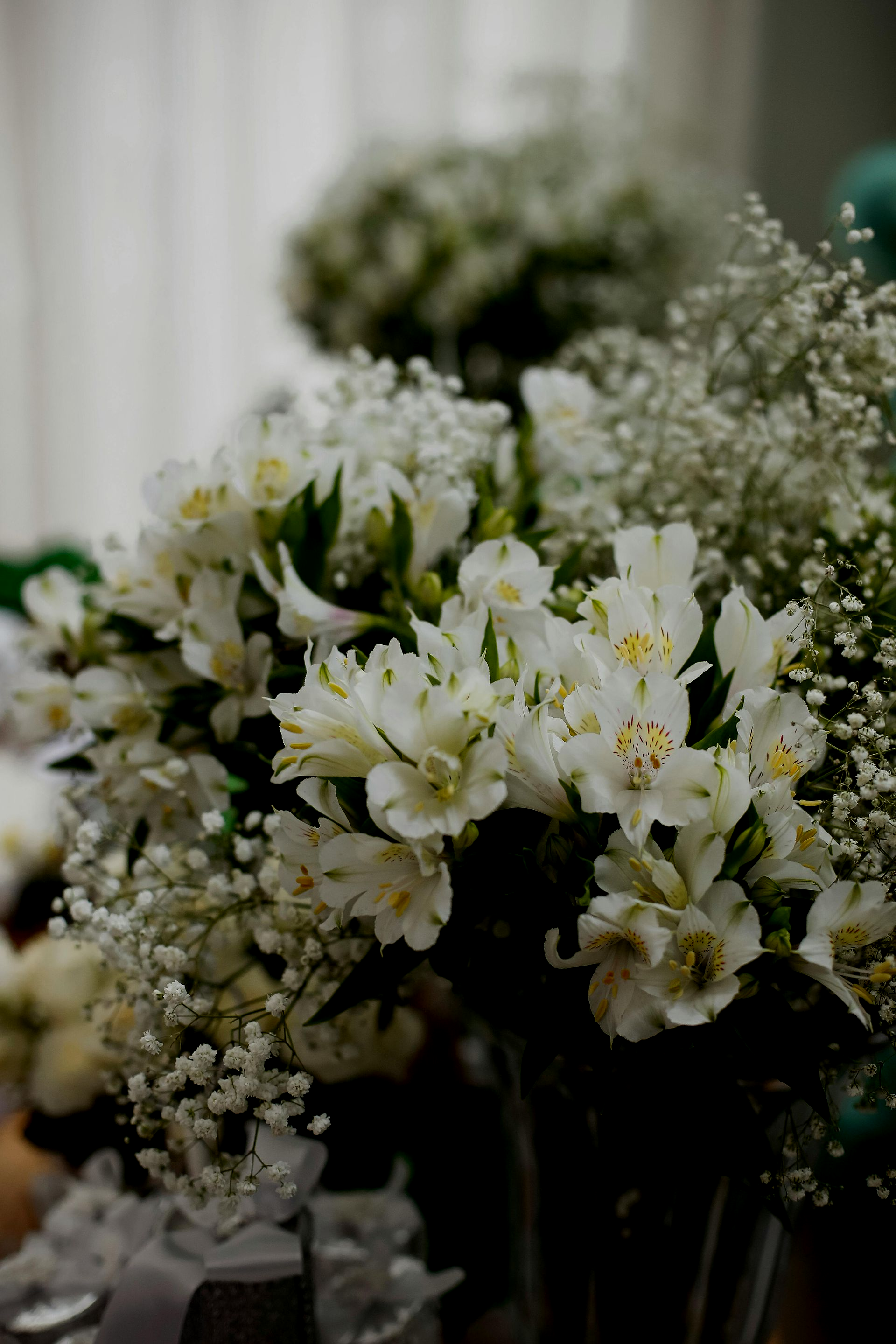A close-up of a bouquet of white Alstroemeria flowers mixed with delicate baby's breath, set against a blurred background.
