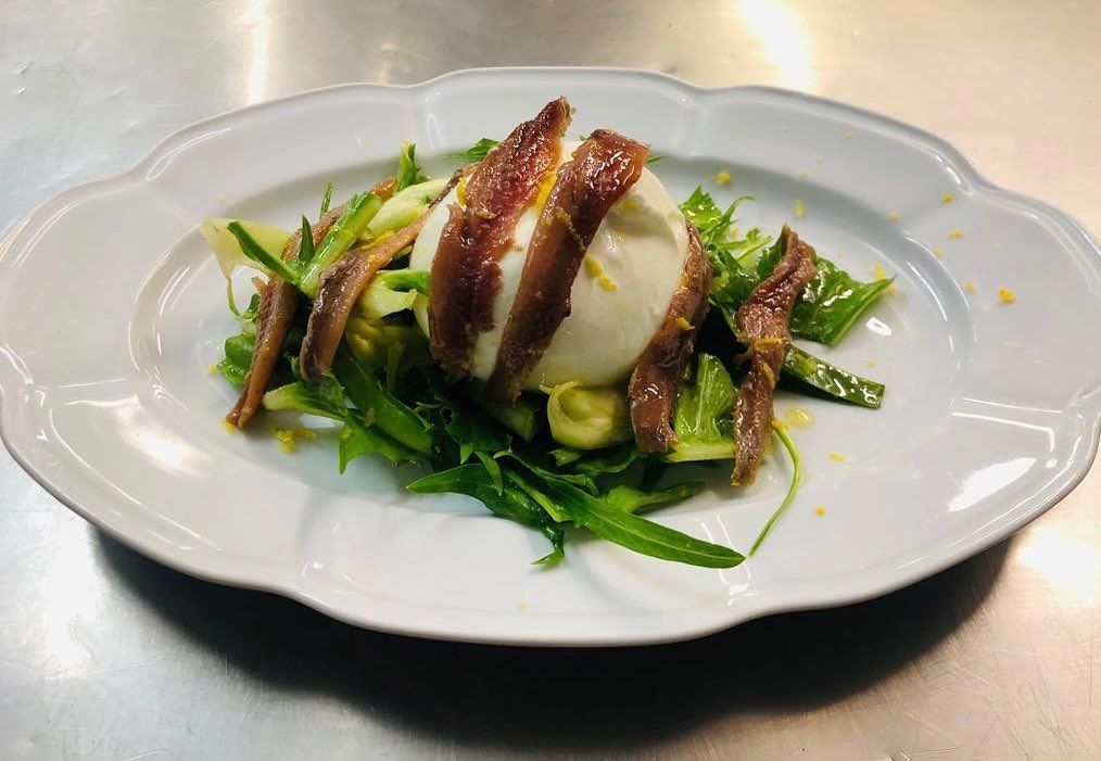 un piatto bianco con insalata e uova su un tavolo .