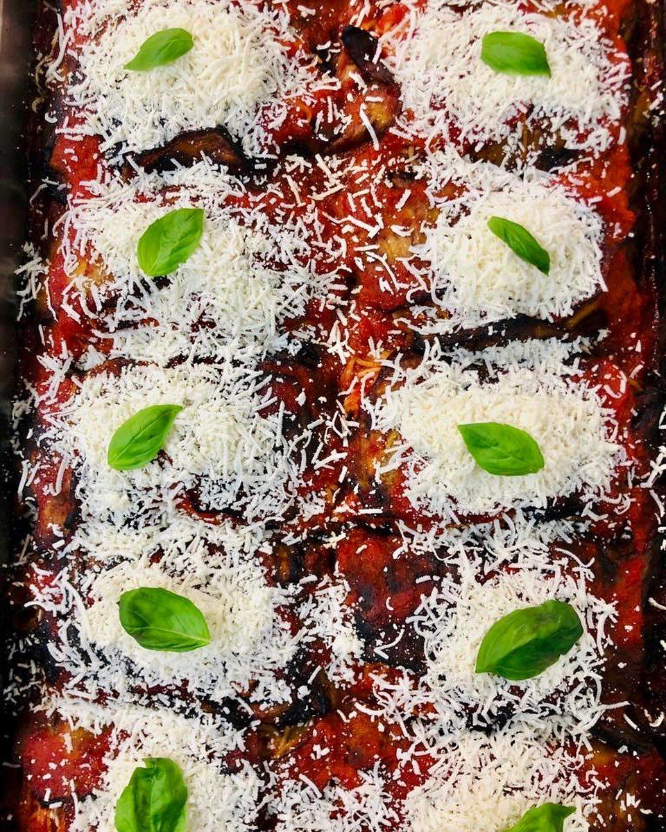 un primo piano di un piatto di cibo con formaggio e basilico