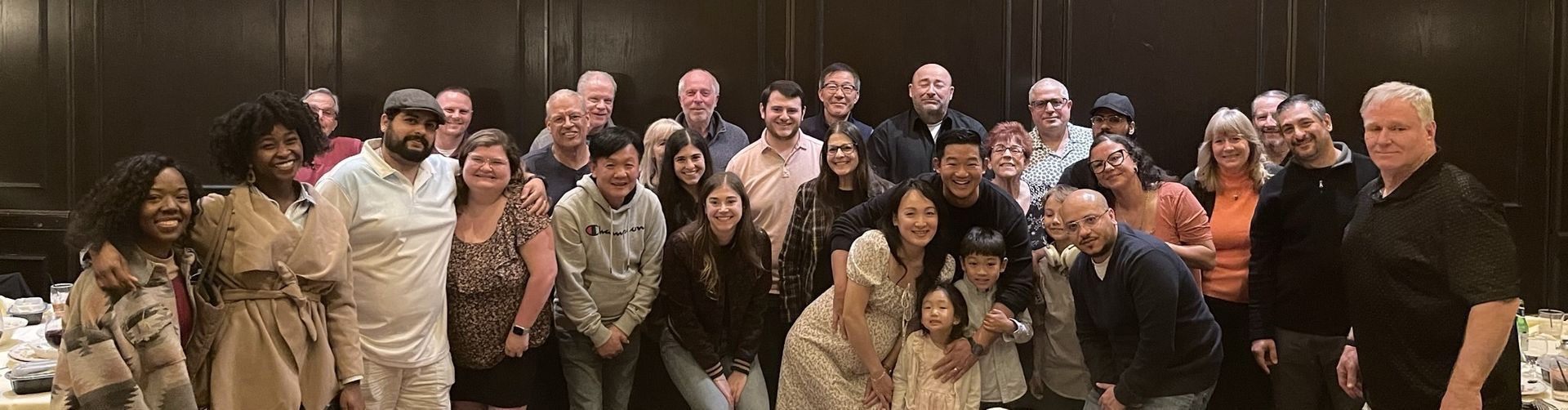 Group photo of Top Driving School company in a dimly lit room, many people smiling and posing for the camera.