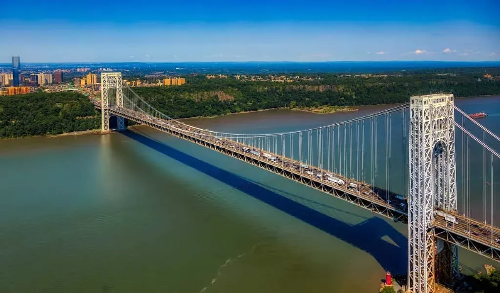 George Washington Bridge over river, clear blue sky, green trees and water.