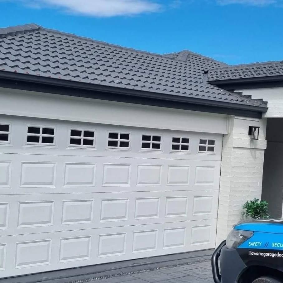 A Blue Truck Is Parked in Front of A White Garage Door — Illawarra Garage Doors in Kiama, NSW