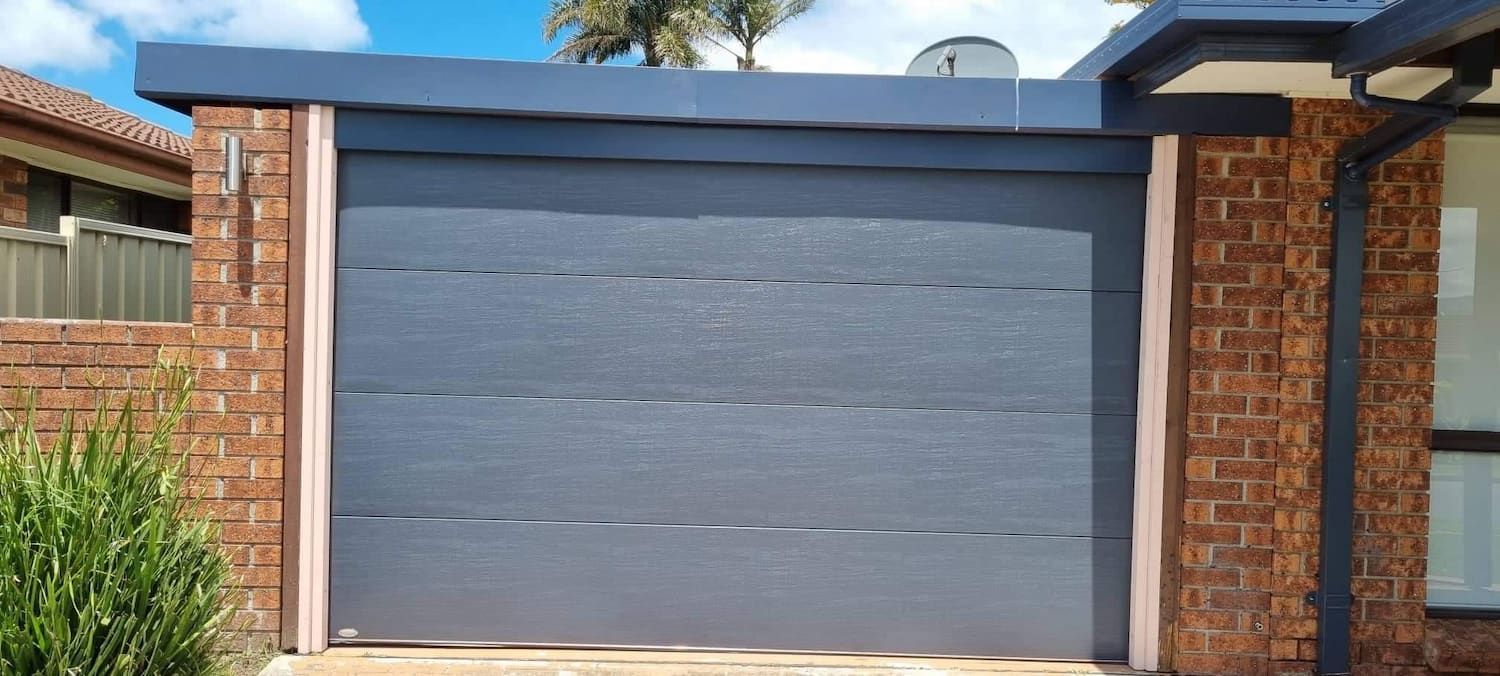 A Wooden Garage Door Is Being Installed on A House — Illawarra Garage Doors in Albion Park Rail, NSW