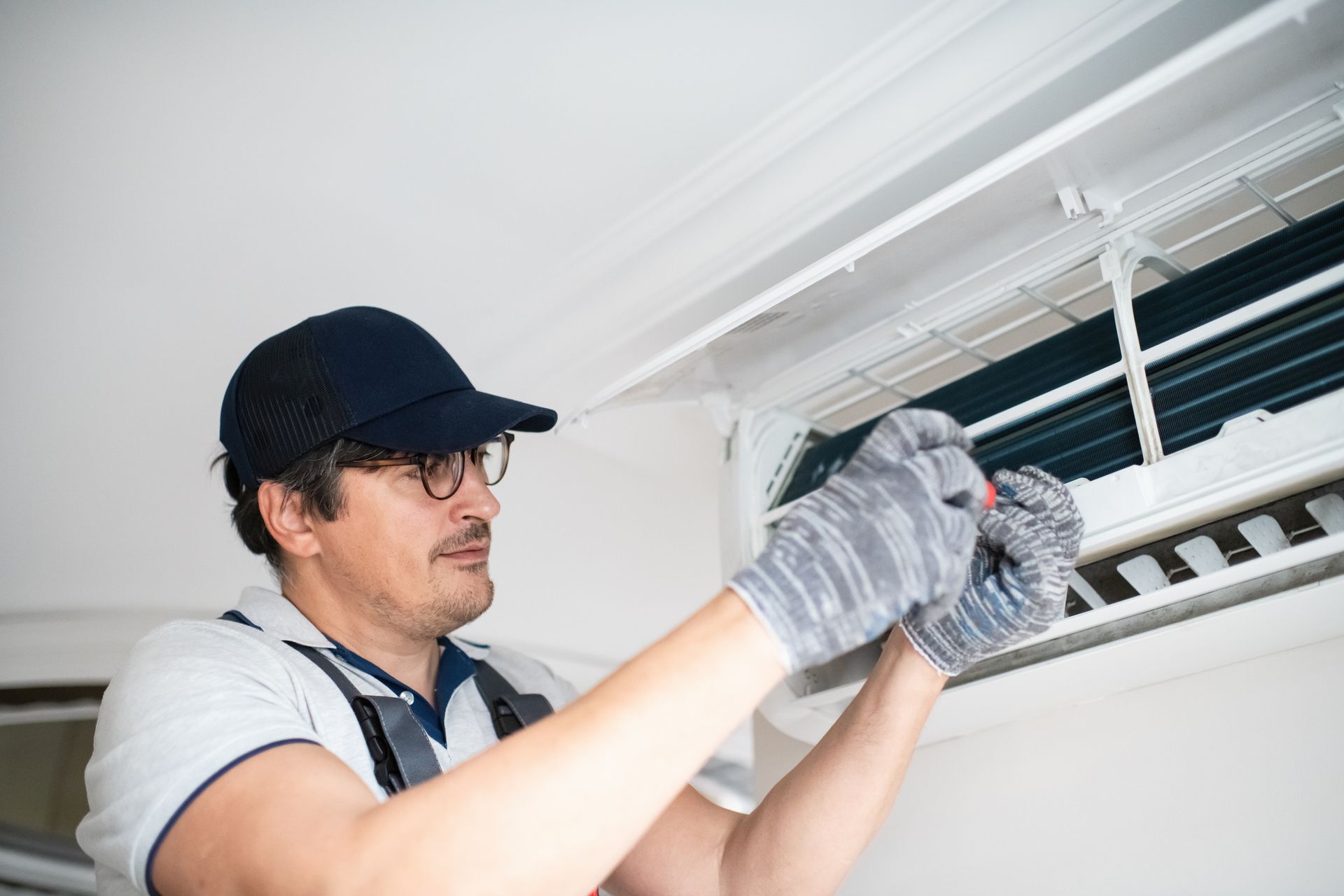 A man is working on an air conditioner in a room.