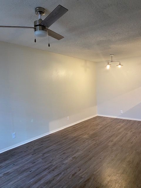 An empty living room with hardwood floors and a ceiling fan.