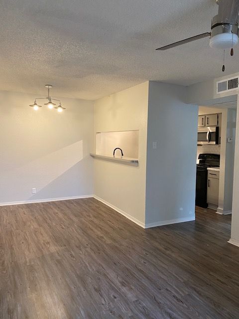 An empty living room with hardwood floors and a ceiling fan.