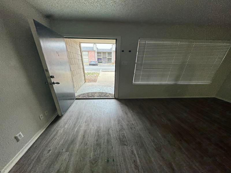 An empty living room with hardwood floors and a door leading to a patio.