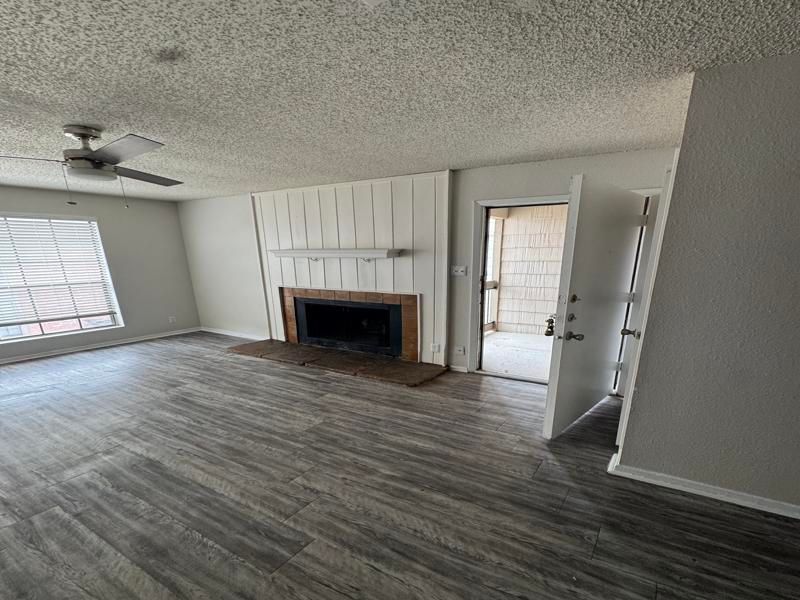 A living room with a fireplace and a ceiling fan.