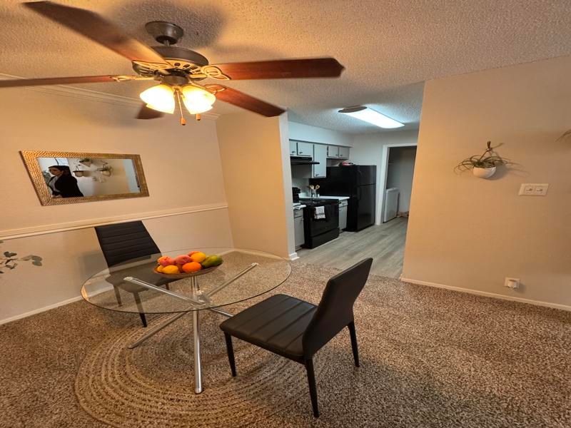 A dining room with a table and chairs and a ceiling fan.
