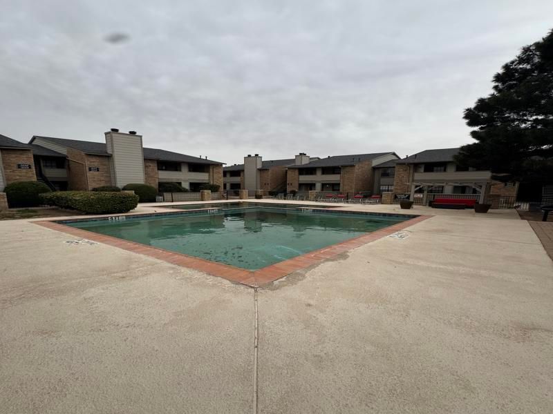 A large swimming pool surrounded by buildings on a cloudy day
