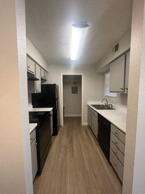 A kitchen with white cabinets and black appliances