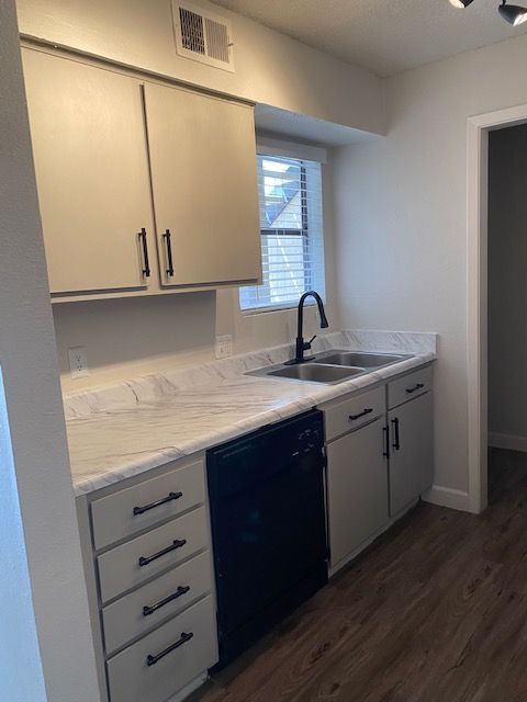 A kitchen with white cabinets and a black dishwasher