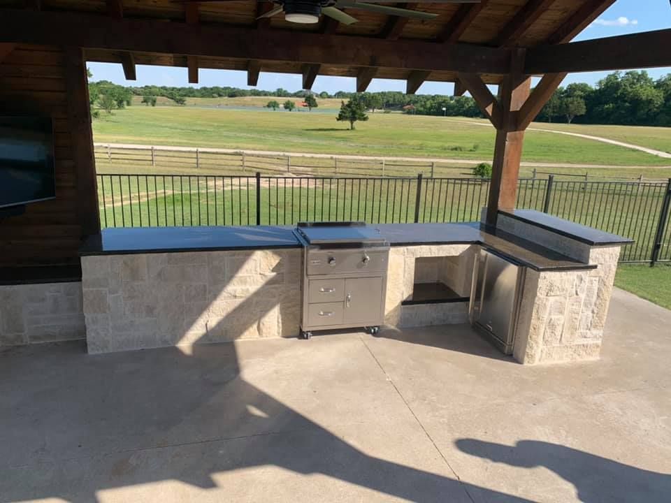 A large outdoor kitchen with a view of a field.