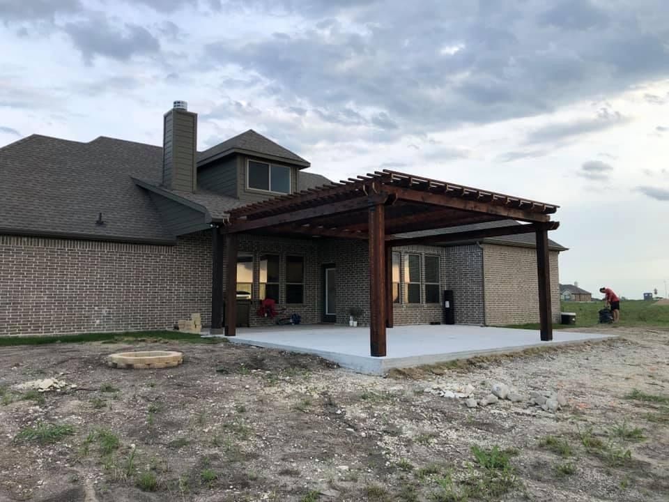 A large brick house with a wooden pergola in front of it.