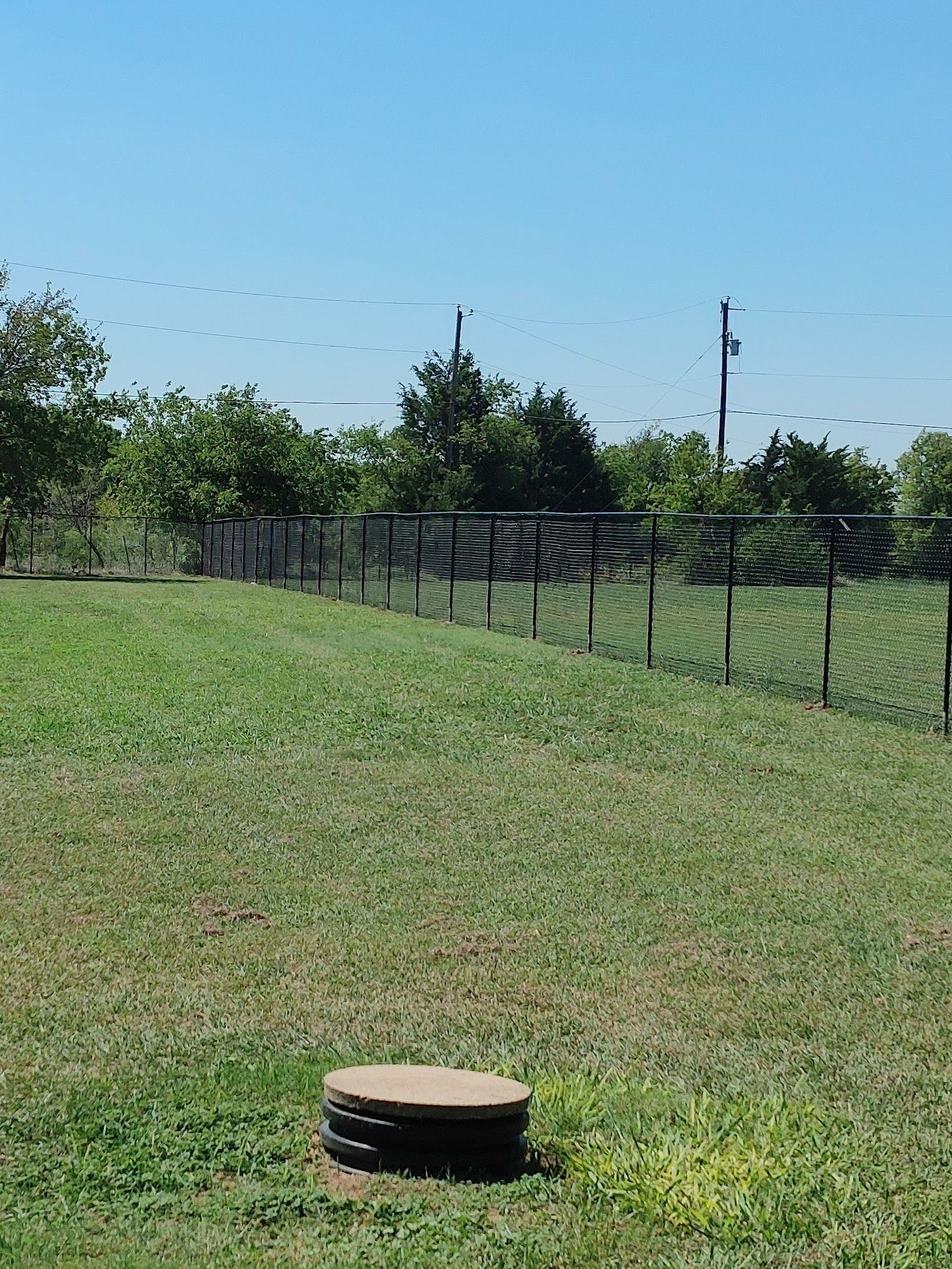 A manhole cover is sitting in the middle of a grassy field.