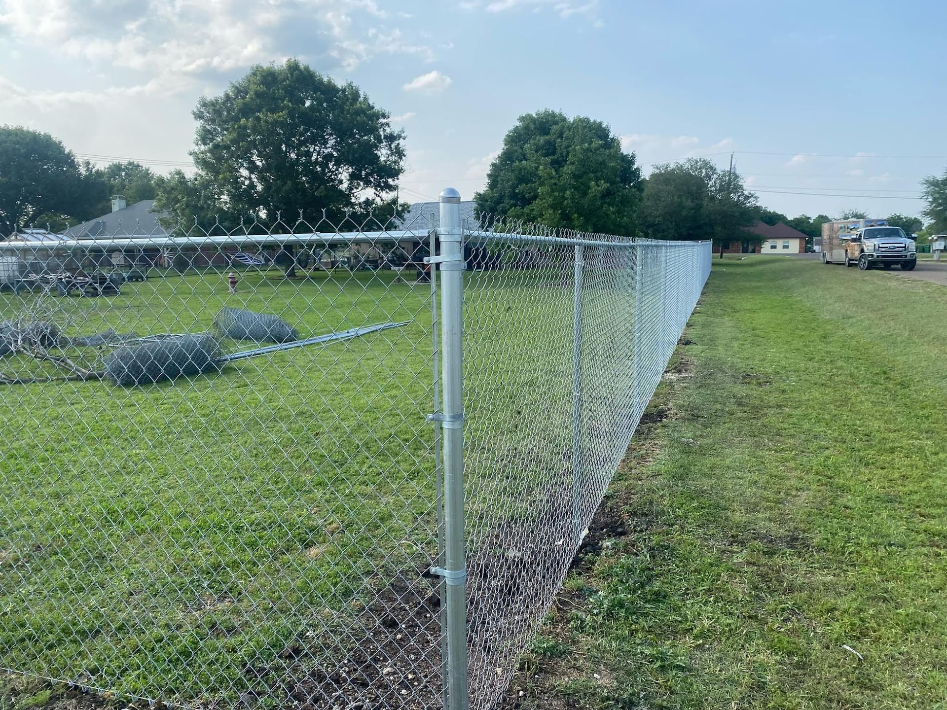 A chain link fence is surrounding a grassy field.