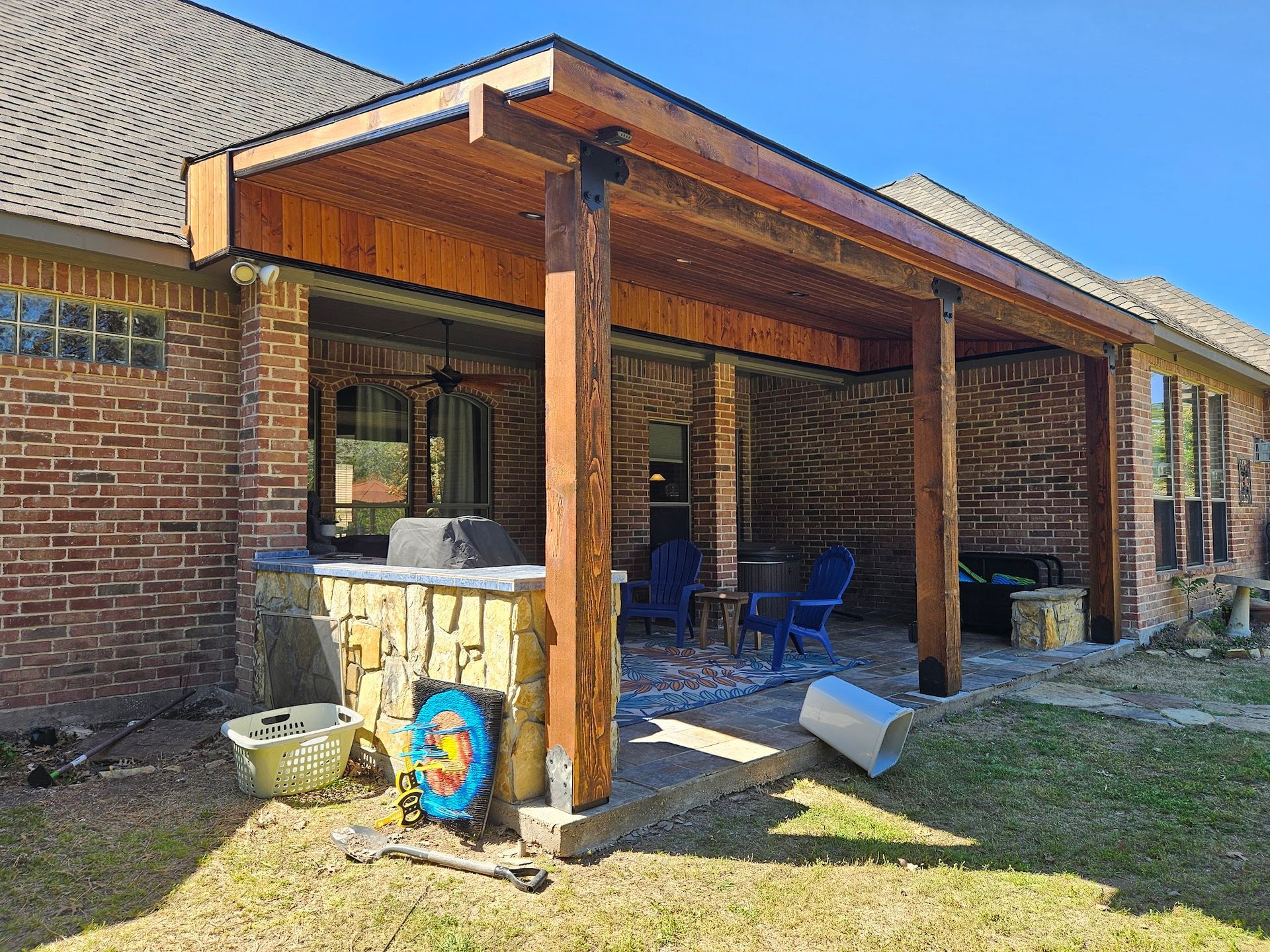 A brick house with a wooden covered patio in the backyard.
