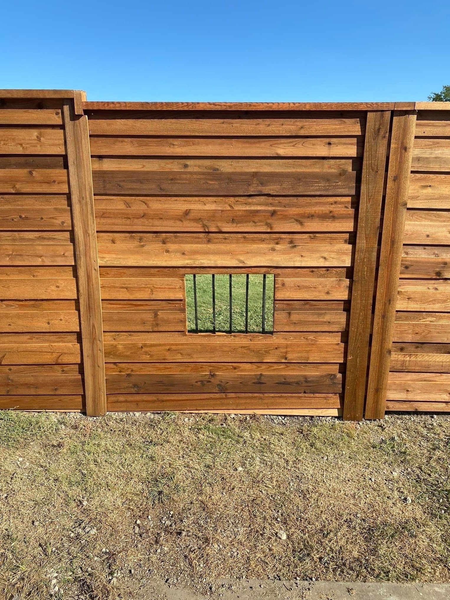 A wooden fence with a small window in the middle of it.
