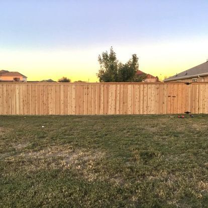 A wooden fence is in the middle of a lush green field.