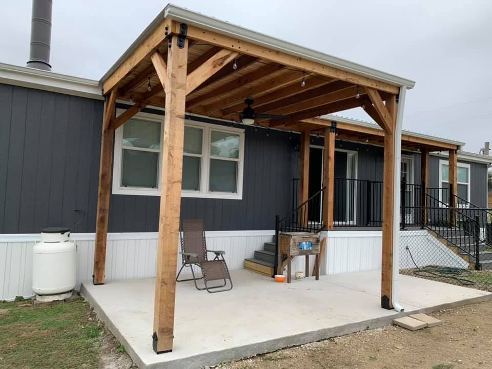 A mobile home with a wooden pergola on the back porch.