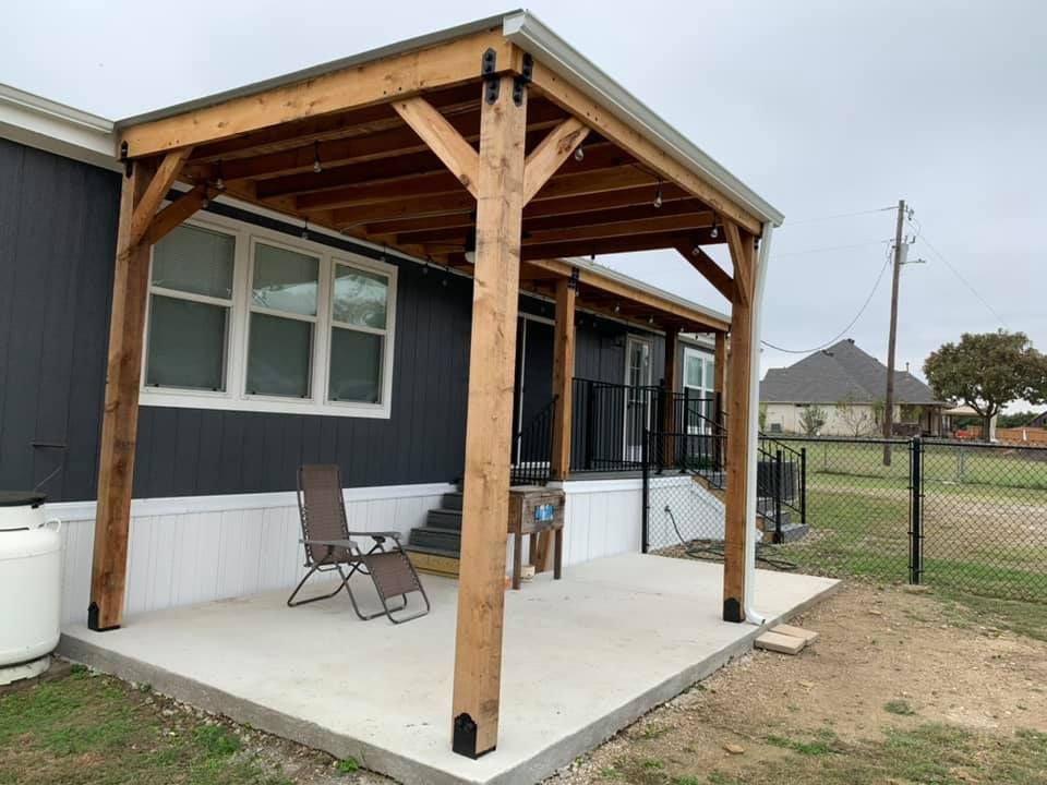 A mobile home with a wooden porch and chairs on it.