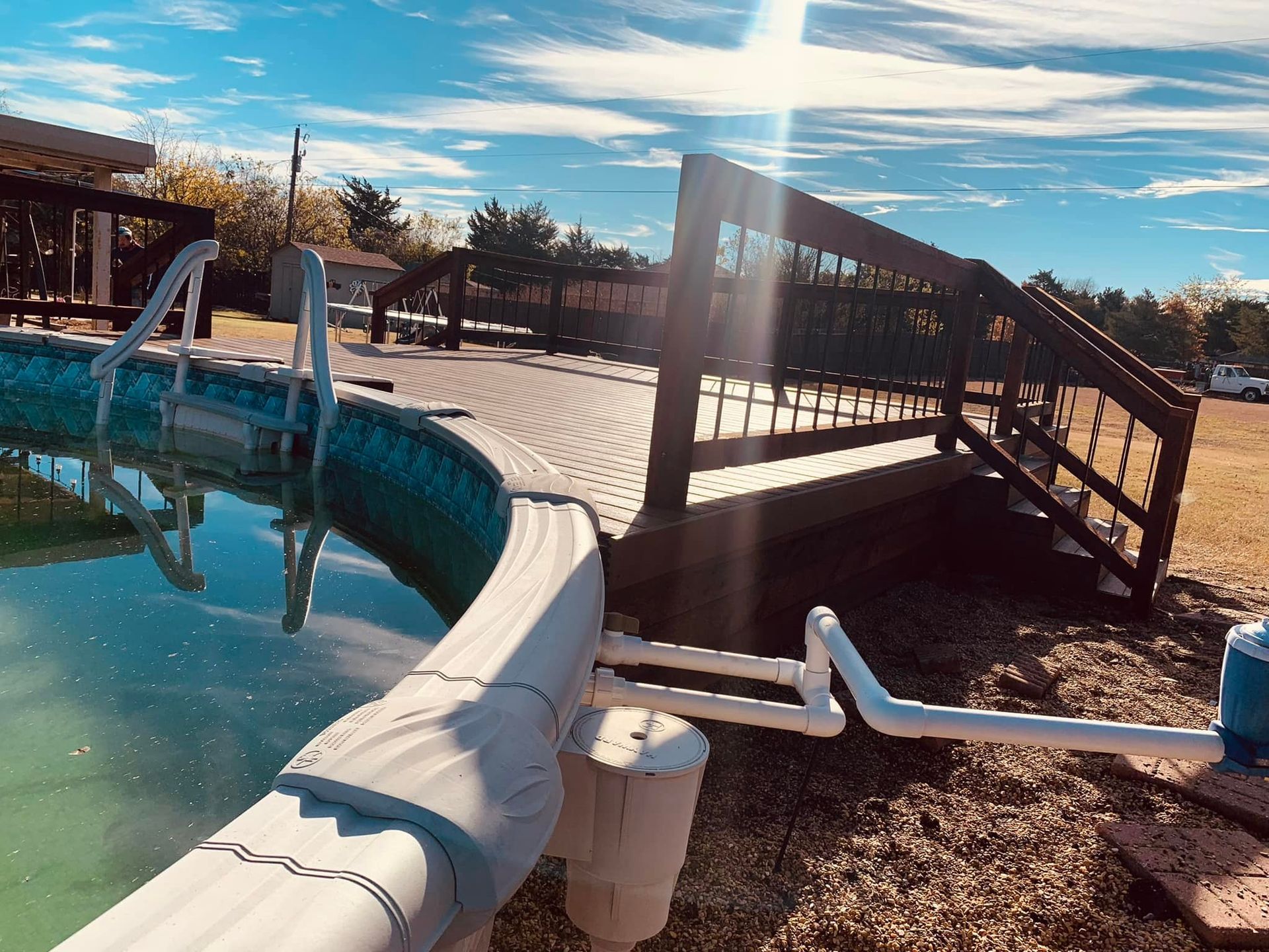 A swimming pool with a wooden bridge in the background