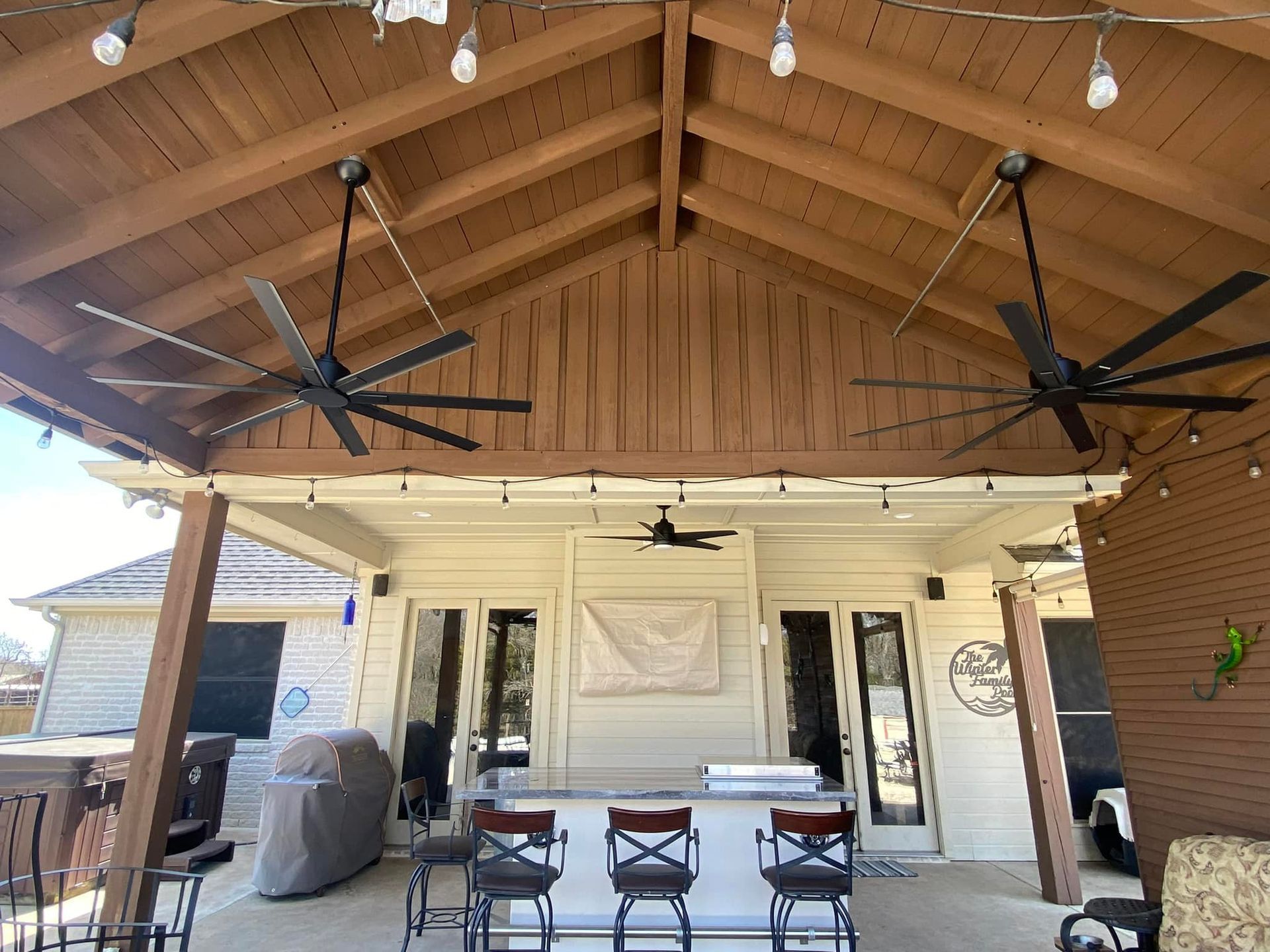 A covered patio with a bar and ceiling fans.
