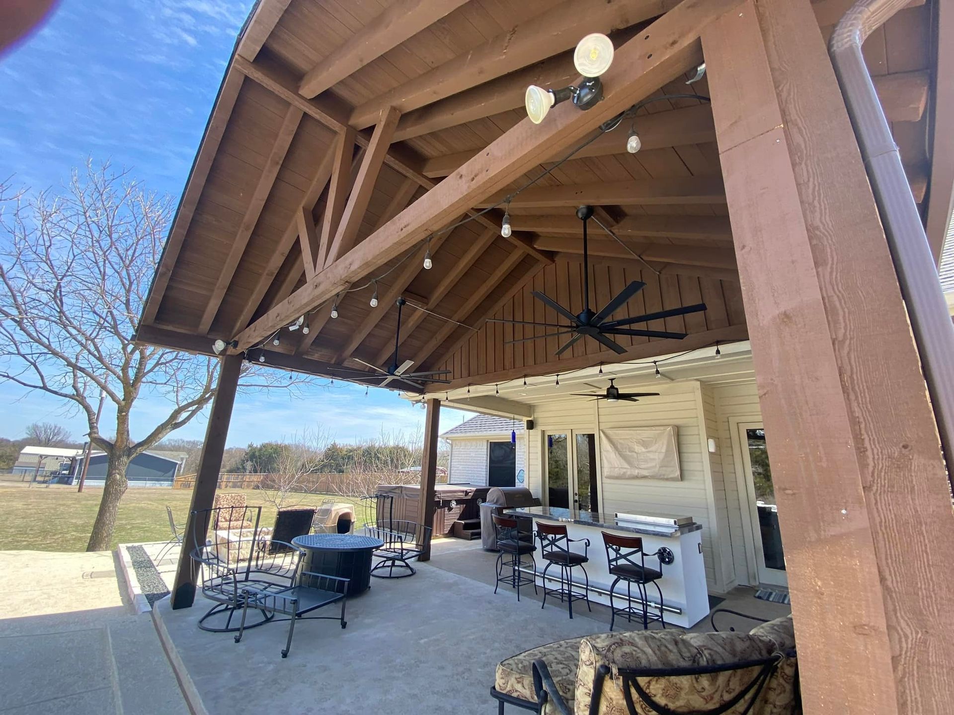 A large covered patio with a ceiling fan and a table and chairs.
