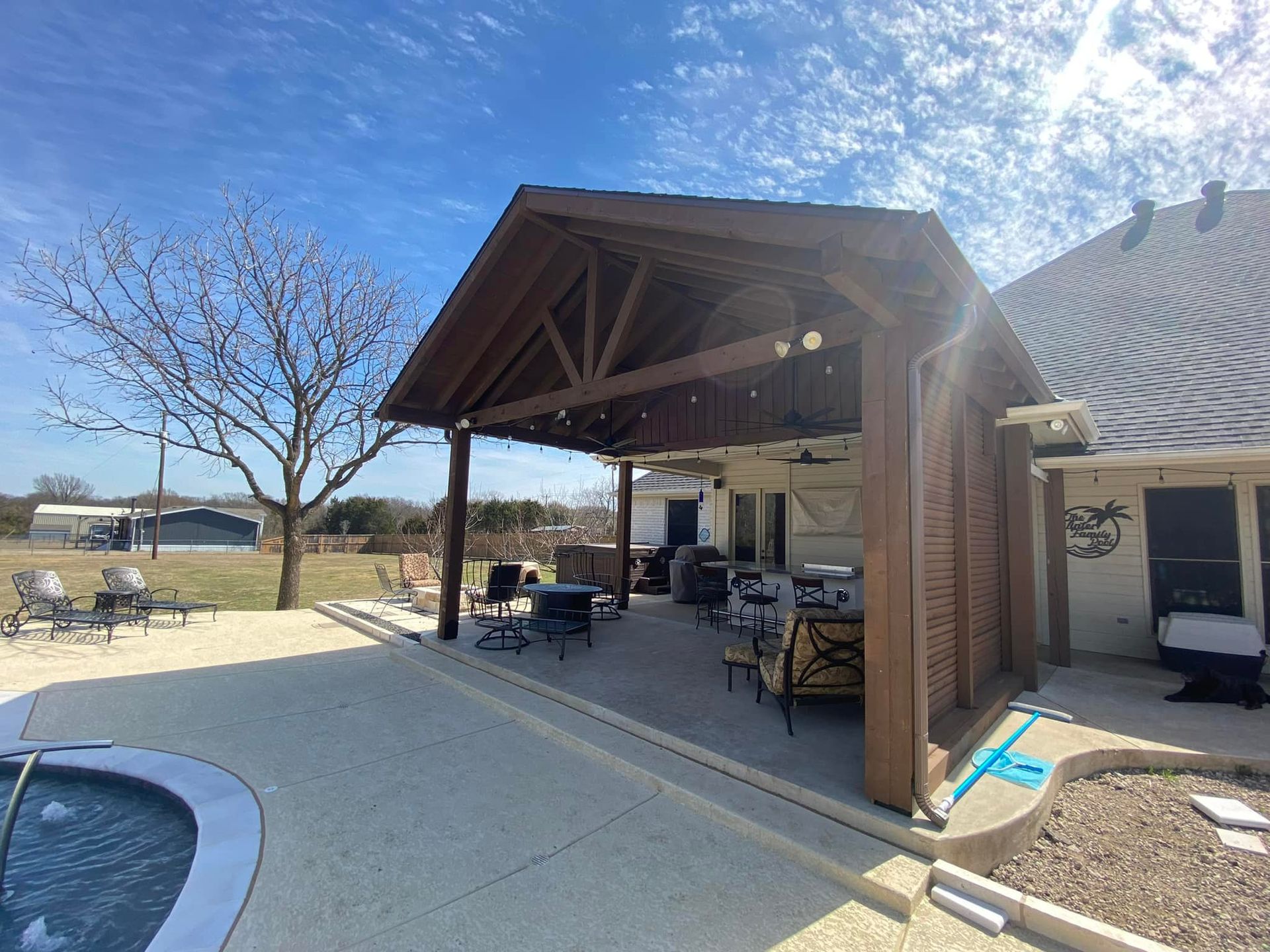 A large covered patio area with a pool in the backyard of a house.