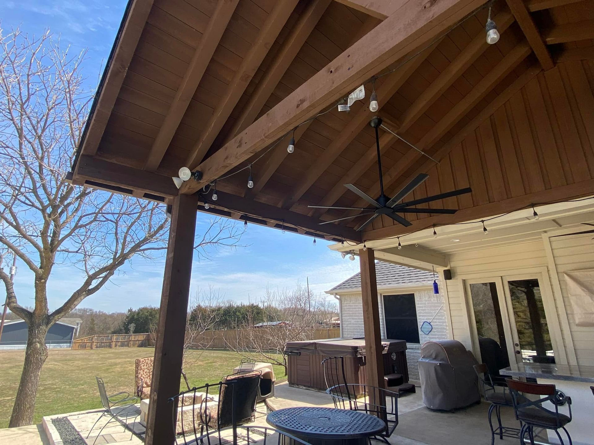 A covered patio with a ceiling fan and a table and chairs.