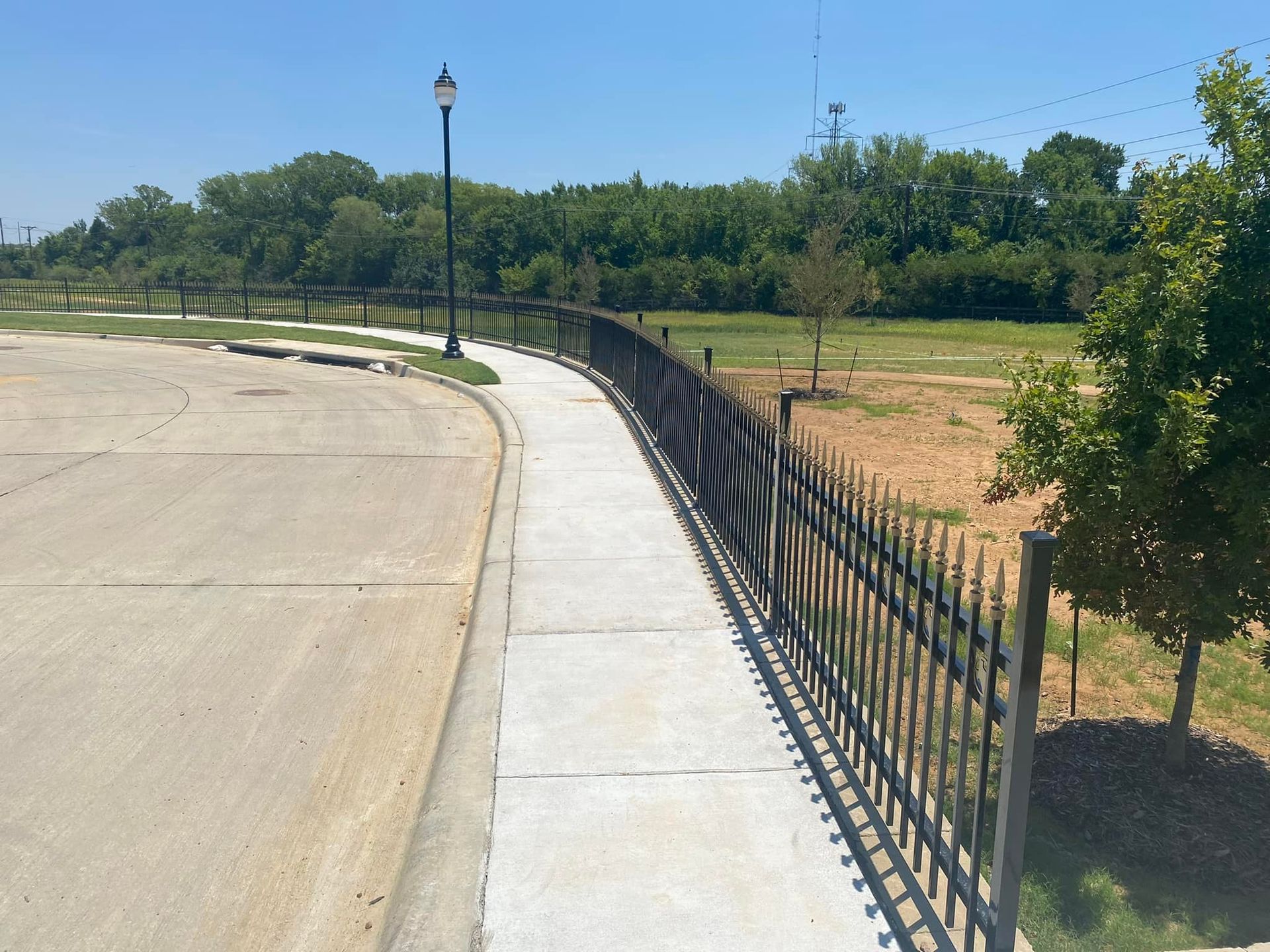 A sidewalk with a wrought iron fence along the side of it