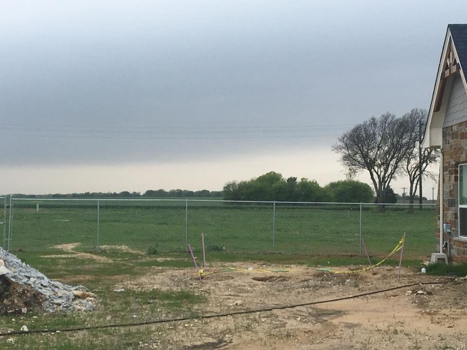 A house in the middle of a field with a fence around it