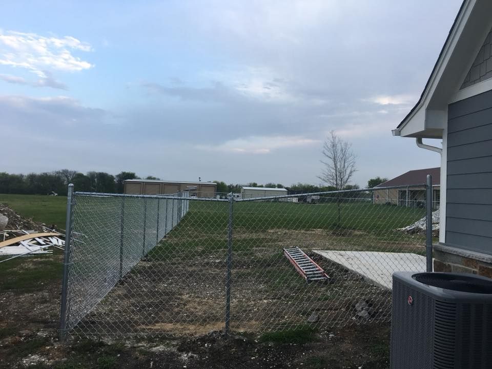 A chain link fence is in the backyard of a house.