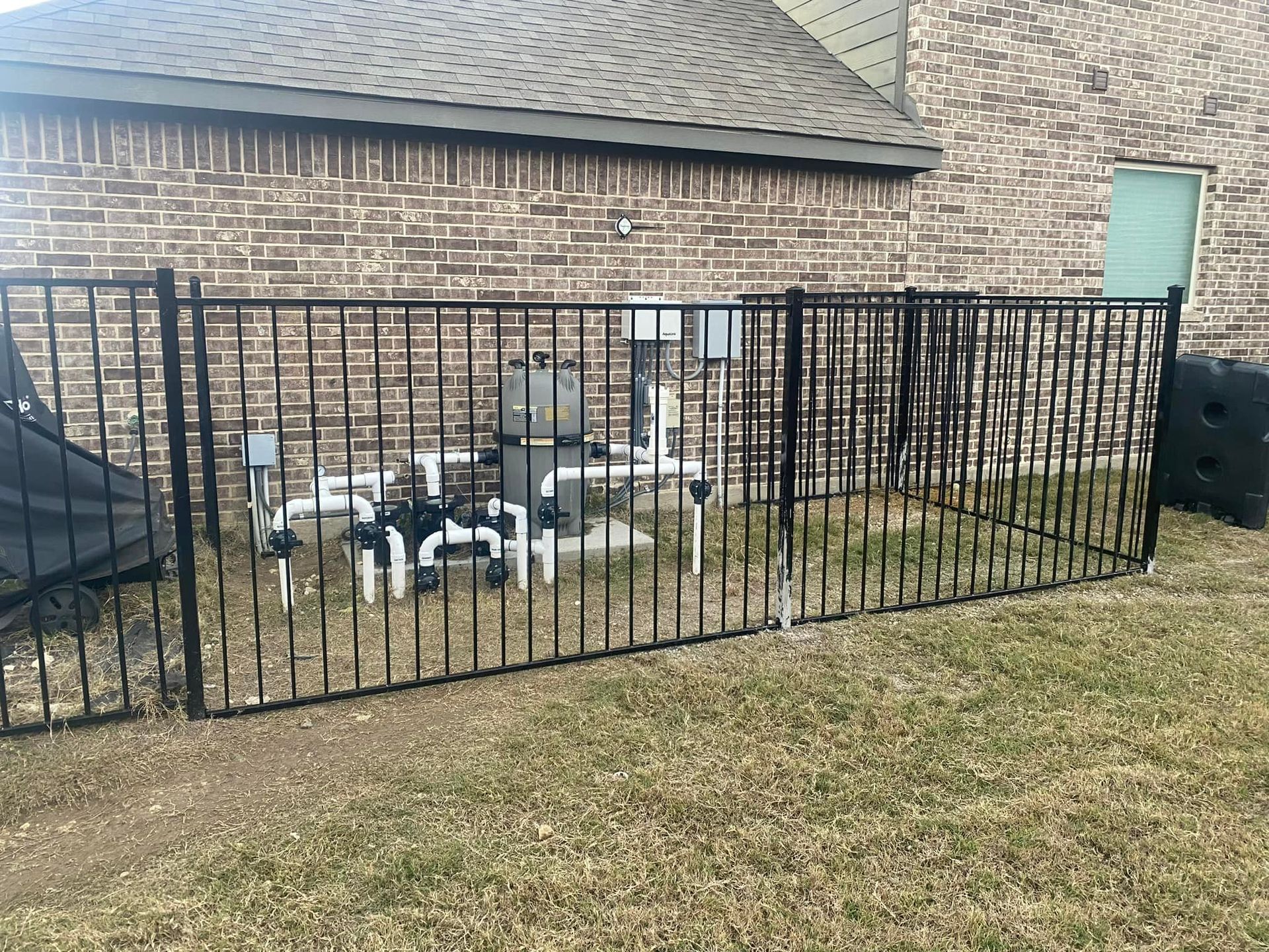 A black metal fence is in front of a brick house.