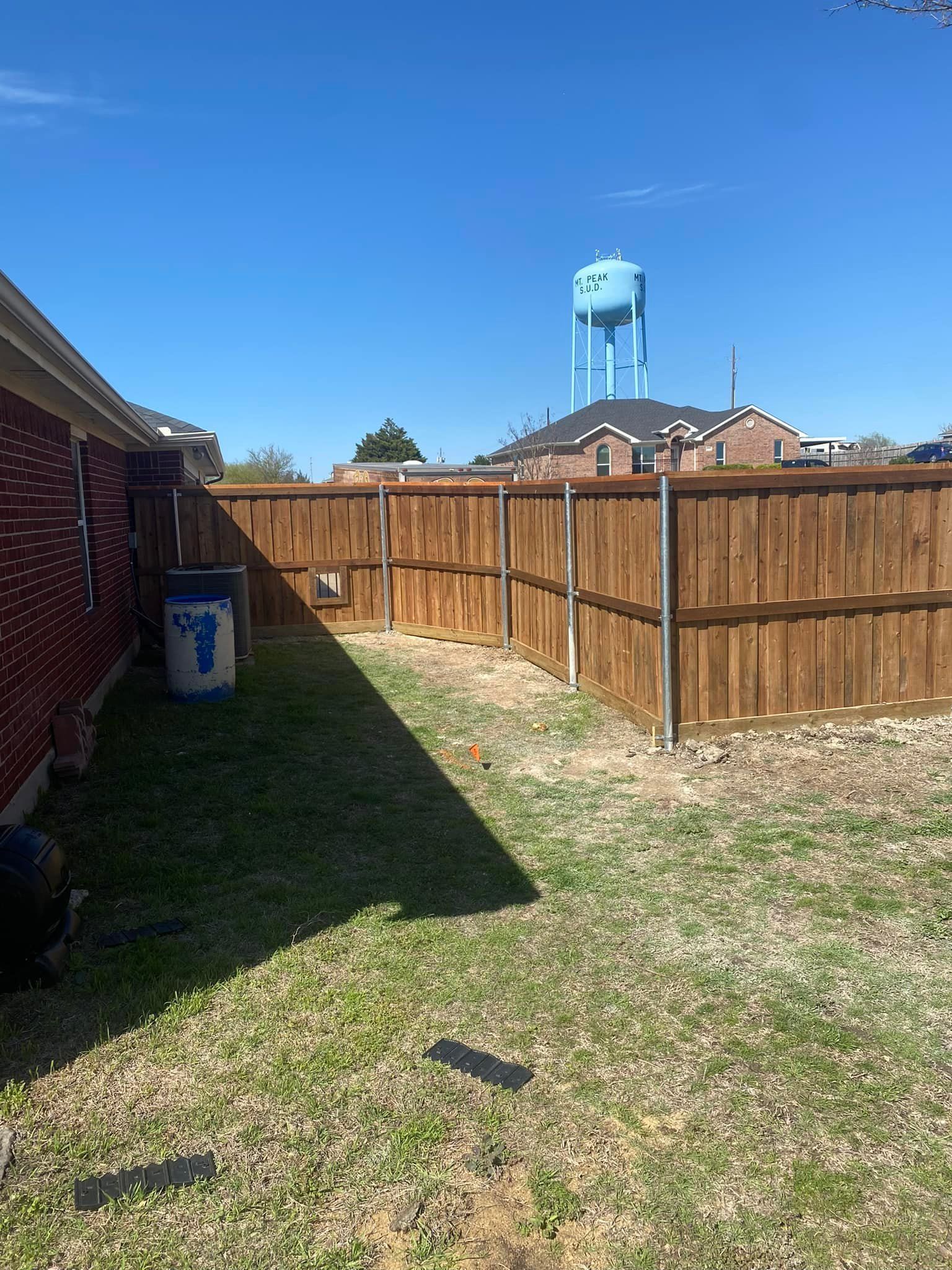 A backyard with a wooden fence and a water tower in the background.