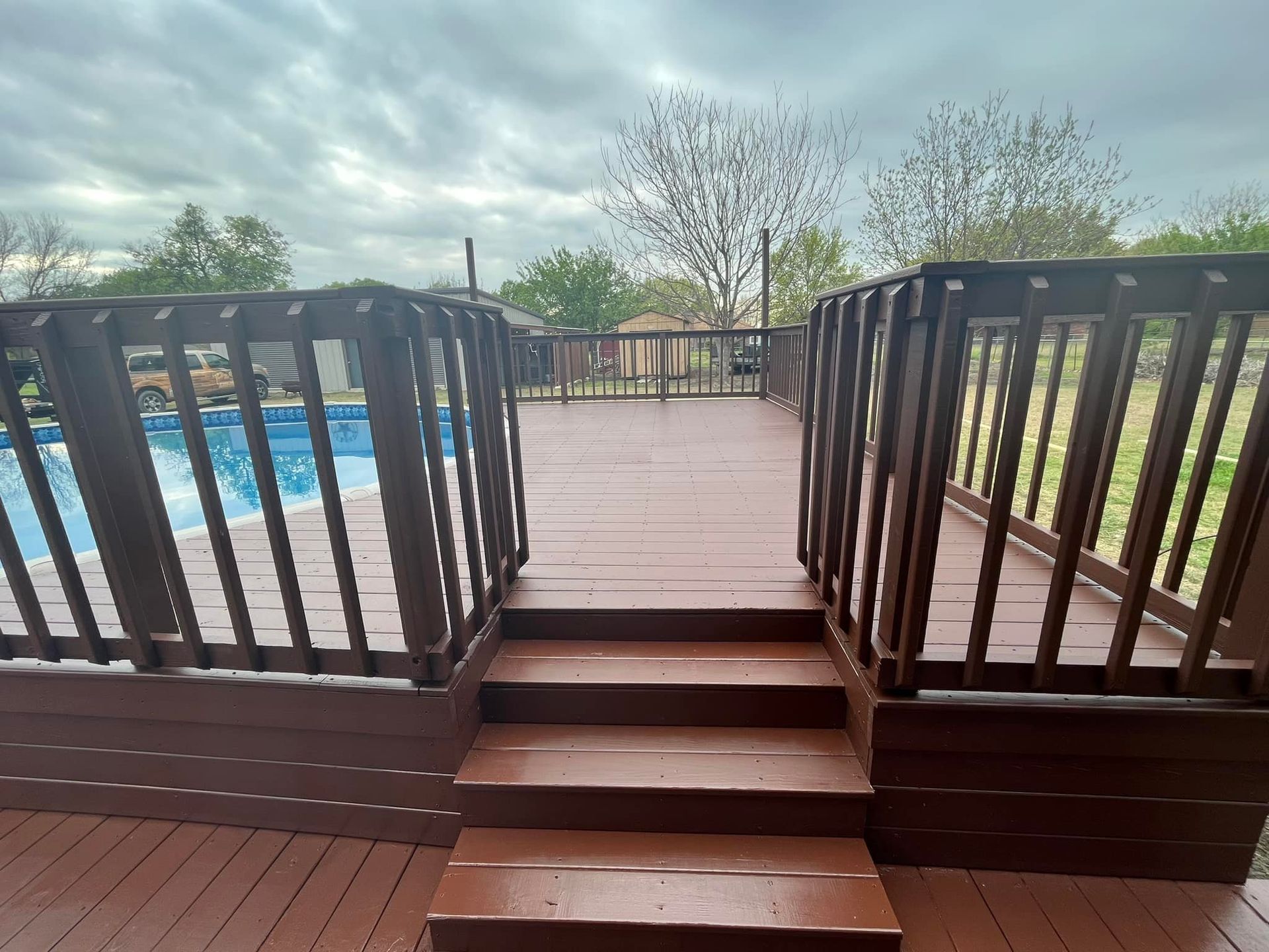 A wooden deck with stairs leading to a swimming pool.